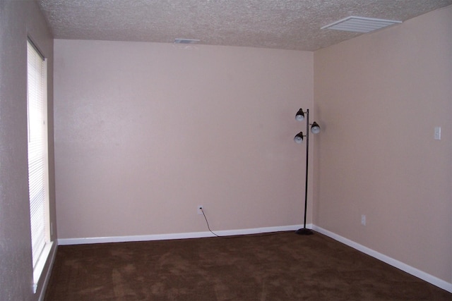 unfurnished room featuring a textured ceiling and dark colored carpet