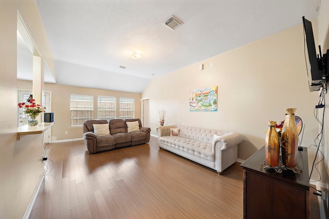 living room featuring light wood-type flooring and vaulted ceiling