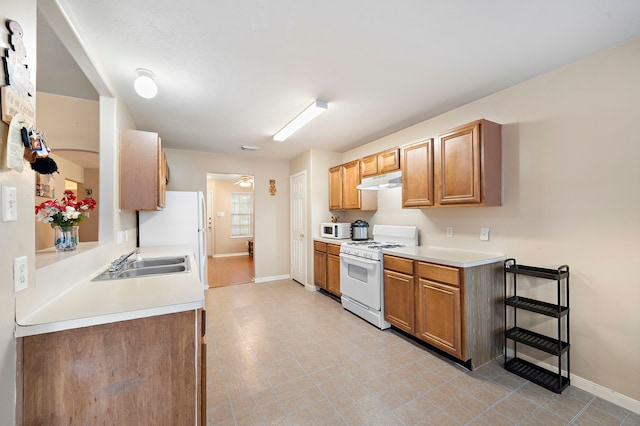 kitchen with light tile patterned floors, white appliances, and sink