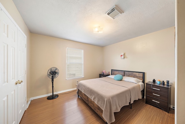 bedroom featuring a closet, light hardwood / wood-style floors, and a textured ceiling