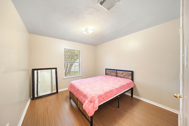 bedroom with hardwood / wood-style flooring and a textured ceiling