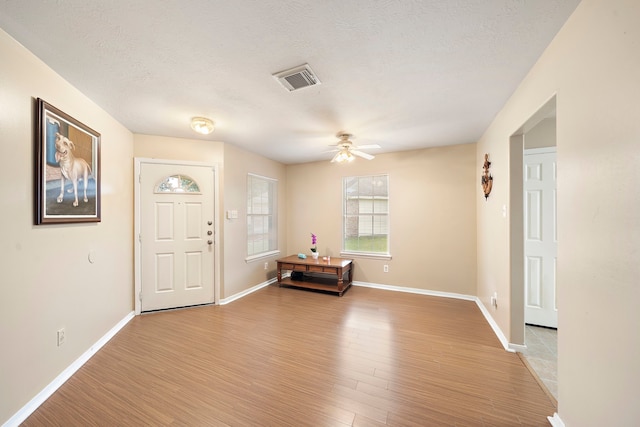 entryway with ceiling fan, light hardwood / wood-style floors, and a textured ceiling