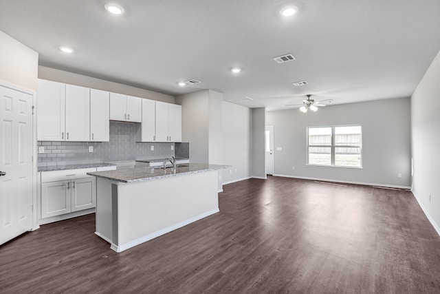 kitchen featuring light stone counters, dark hardwood / wood-style flooring, white cabinetry, ceiling fan, and decorative backsplash