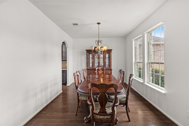 dining space with dark hardwood / wood-style floors, a notable chandelier, and a healthy amount of sunlight