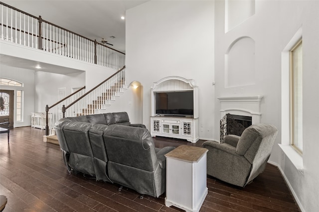 living room with ceiling fan, a towering ceiling, and dark hardwood / wood-style flooring