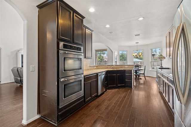 kitchen with stainless steel appliances, dark hardwood / wood-style floors, backsplash, and kitchen peninsula