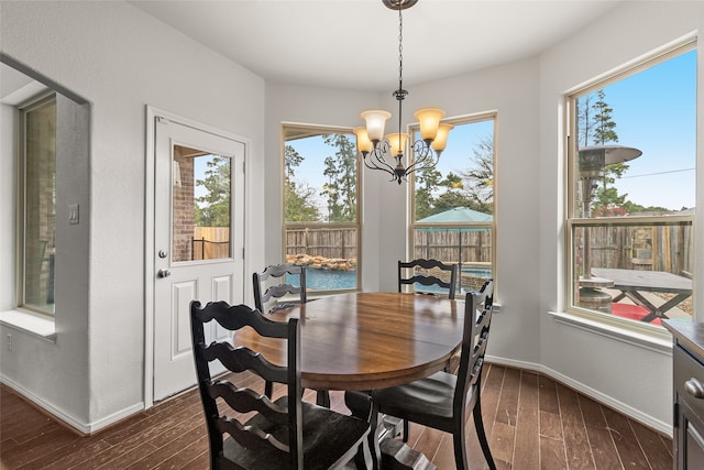 dining room with dark wood-type flooring, a healthy amount of sunlight, and a chandelier