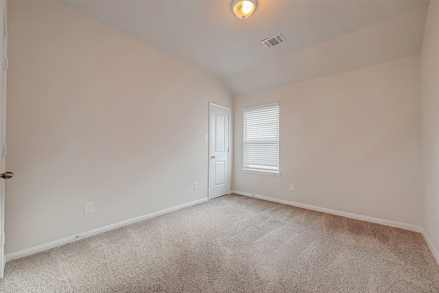 carpeted spare room with vaulted ceiling