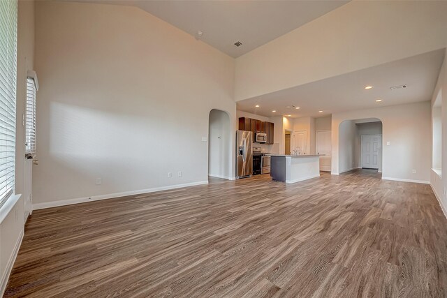 unfurnished living room featuring sink, high vaulted ceiling, and hardwood / wood-style flooring