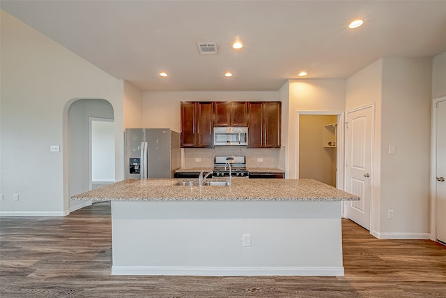 kitchen with a kitchen island with sink, backsplash, stainless steel appliances, dark hardwood / wood-style flooring, and sink