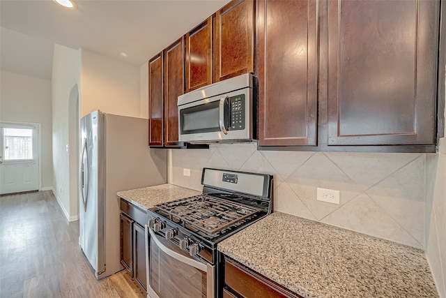 kitchen with backsplash, stainless steel appliances, and light hardwood / wood-style flooring