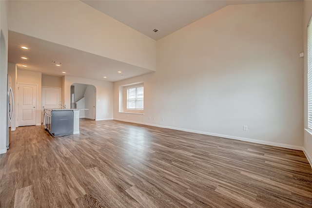 unfurnished living room featuring lofted ceiling, wood-type flooring, and sink