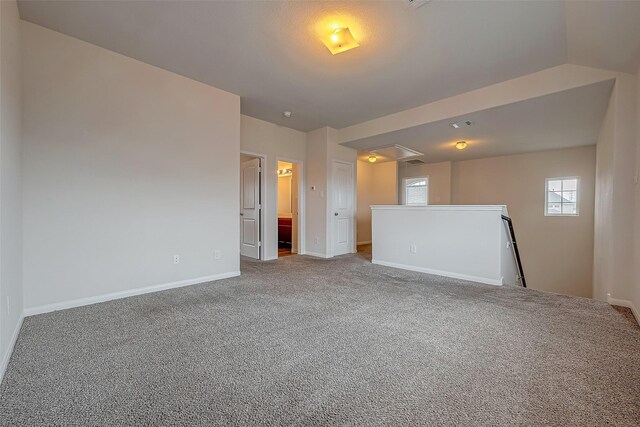 carpeted empty room with vaulted ceiling