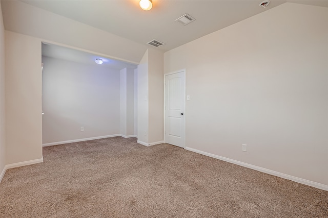 carpeted spare room with vaulted ceiling