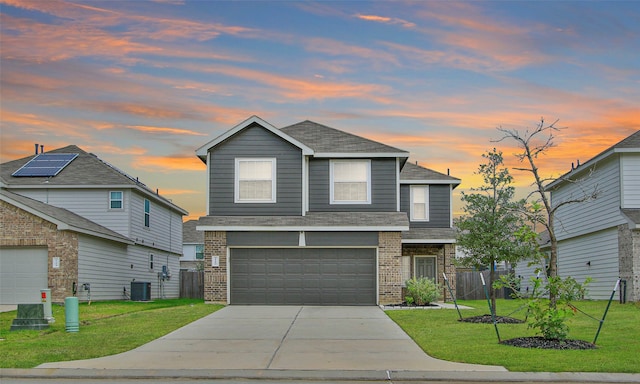 view of front of house with a garage, central AC unit, a yard, and solar panels