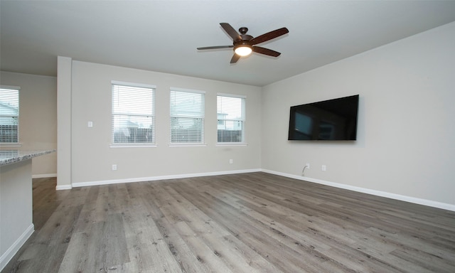 unfurnished living room featuring ceiling fan and hardwood / wood-style flooring