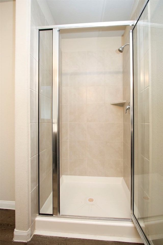 bathroom with hardwood / wood-style flooring and walk in shower