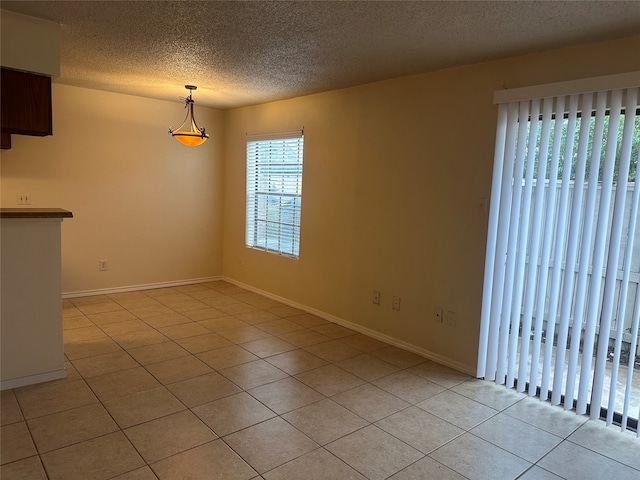 interior space with a textured ceiling, plenty of natural light, and light tile patterned floors