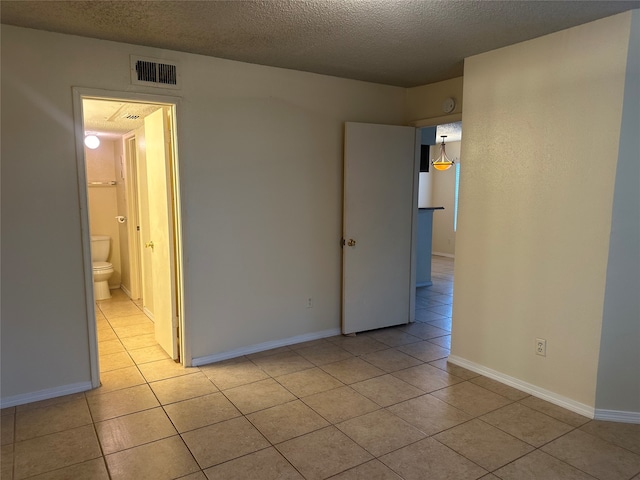 unfurnished room featuring a textured ceiling and light tile patterned floors