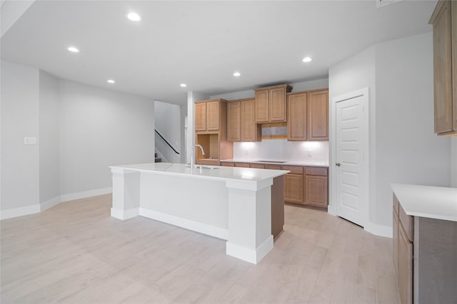 kitchen featuring light hardwood / wood-style floors, a center island with sink, sink, backsplash, and black stovetop