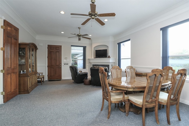 carpeted dining space with a wealth of natural light, crown molding, and ceiling fan