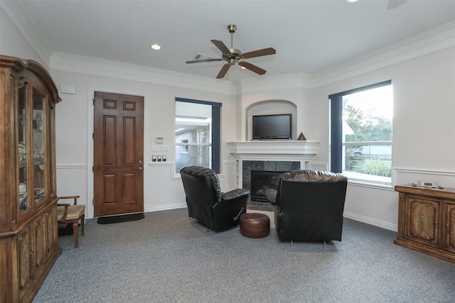 carpeted living room featuring crown molding, ceiling fan, and a fireplace