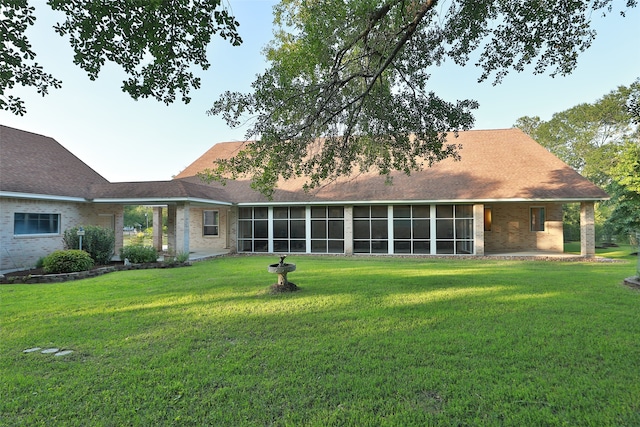 rear view of house featuring a lawn and a sunroom