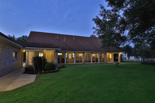 back house at dusk featuring a yard