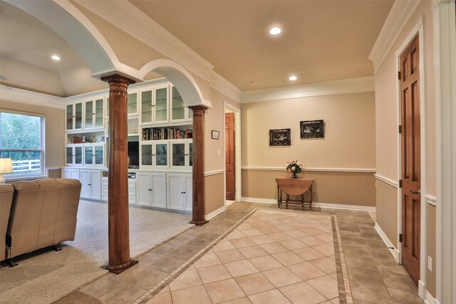 corridor with crown molding, light tile patterned floors, and decorative columns