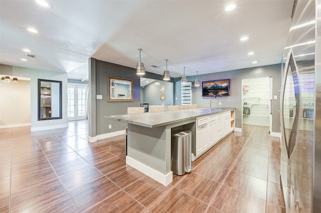 kitchen with tile patterned floors, decorative light fixtures, stainless steel refrigerator with ice dispenser, french doors, and white cabinets