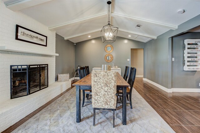 dining area featuring hardwood / wood-style flooring, vaulted ceiling with beams, and a fireplace