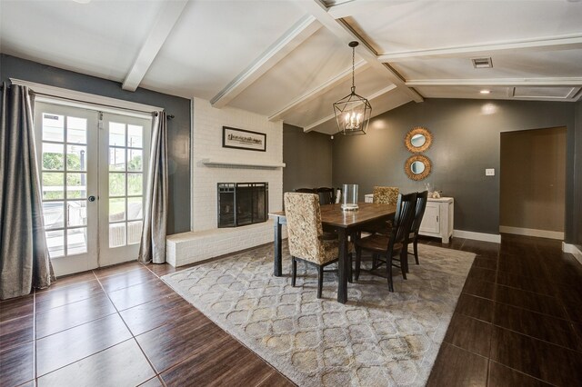 dining room featuring a fireplace, an inviting chandelier, lofted ceiling with beams, french doors, and dark hardwood / wood-style flooring