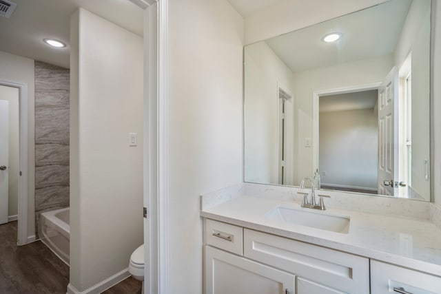 bathroom featuring a tub to relax in, vanity, toilet, and hardwood / wood-style floors