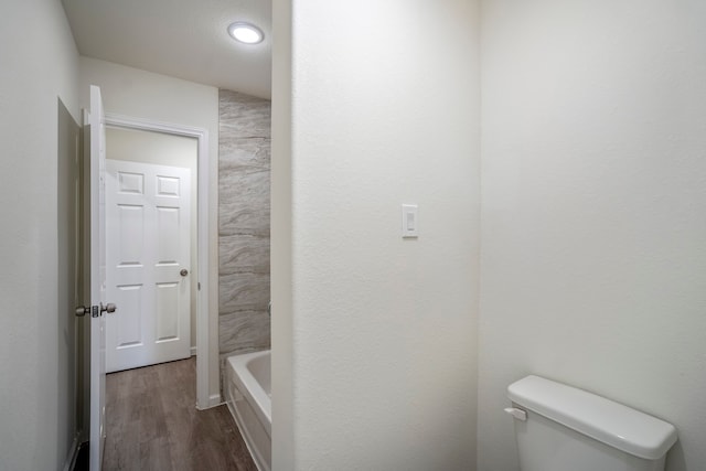 bathroom featuring toilet, hardwood / wood-style floors, and a washtub