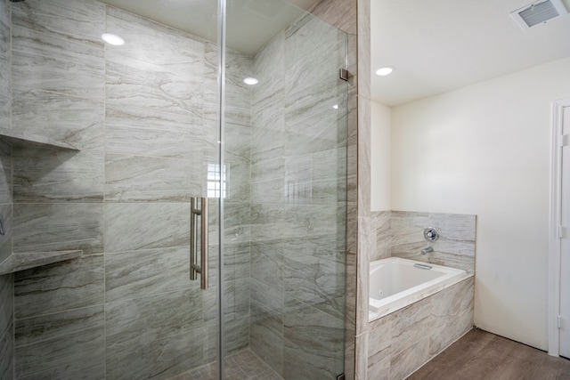 bathroom featuring hardwood / wood-style flooring and plus walk in shower