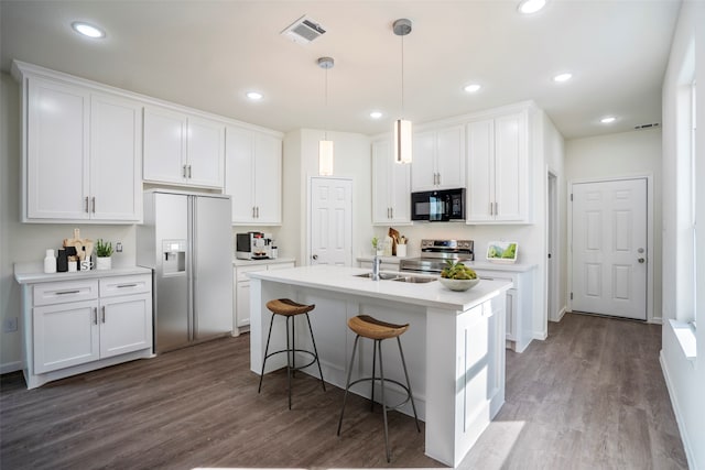 kitchen with a kitchen island with sink, hardwood / wood-style flooring, stainless steel appliances, and white cabinets