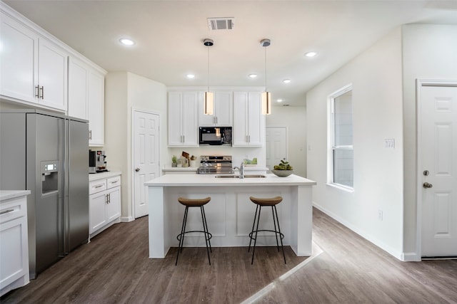 kitchen featuring dark wood-type flooring, stainless steel appliances, and an island with sink