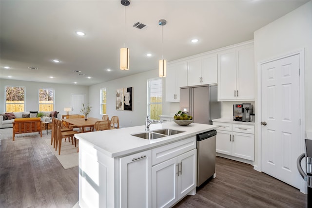 kitchen featuring appliances with stainless steel finishes, dark hardwood / wood-style flooring, white cabinetry, sink, and a center island with sink