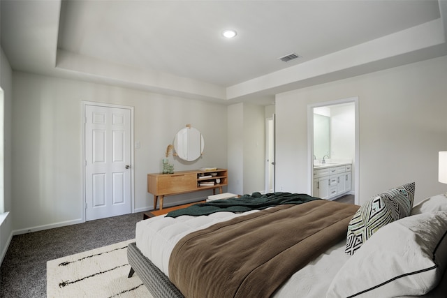 carpeted bedroom with ensuite bath, sink, and a tray ceiling