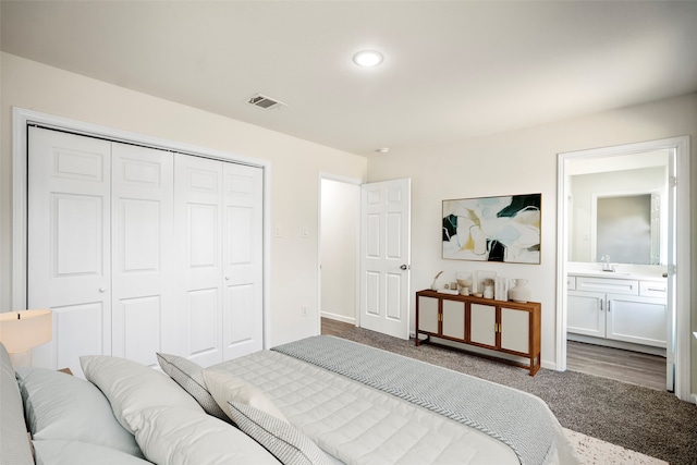 bedroom with a closet, ensuite bath, sink, and hardwood / wood-style floors