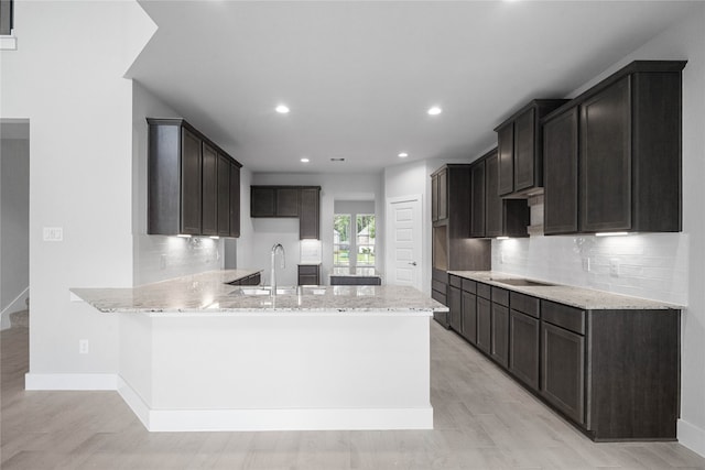 kitchen featuring kitchen peninsula, sink, light wood-type flooring, and light stone countertops