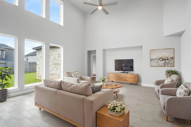 living room featuring light wood-type flooring, ceiling fan, and a high ceiling