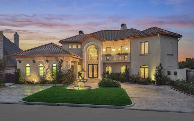 mediterranean / spanish-style home featuring concrete driveway, a yard, french doors, and a tile roof