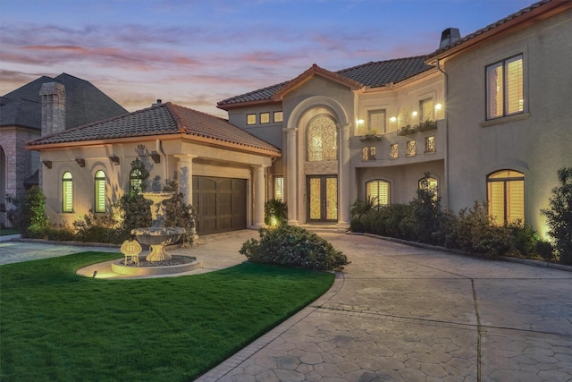 mediterranean / spanish-style home with a tiled roof, concrete driveway, stucco siding, a chimney, and a garage