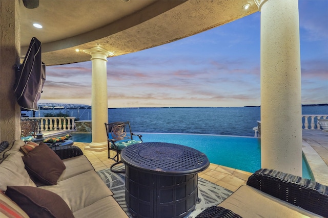 patio terrace at dusk featuring a water view