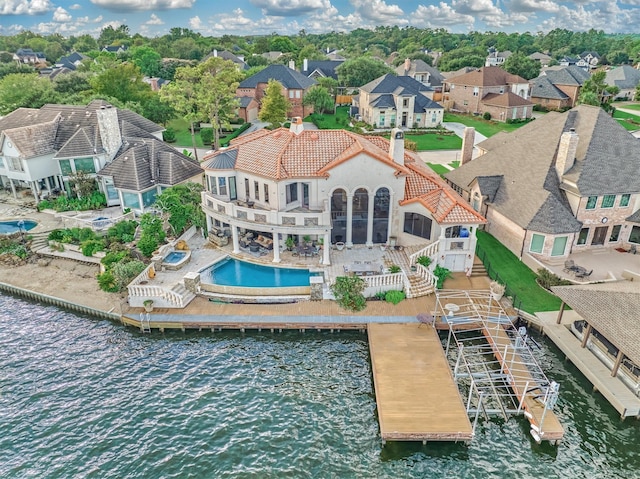 rear view of property with a residential view, a tiled roof, a balcony, and a water view