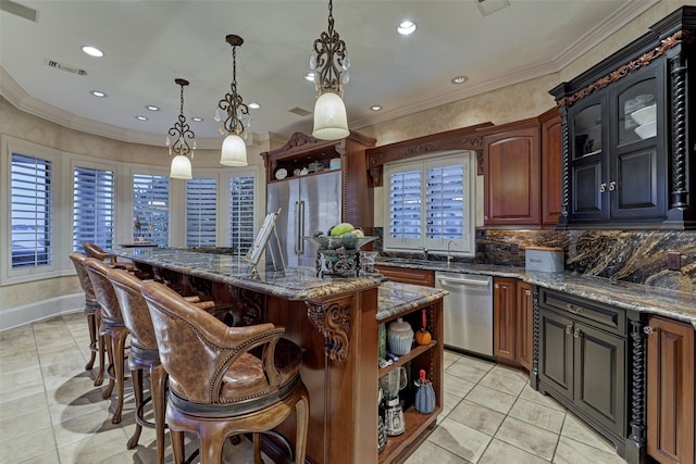 kitchen with dark stone countertops, tasteful backsplash, stainless steel appliances, decorative light fixtures, and a center island