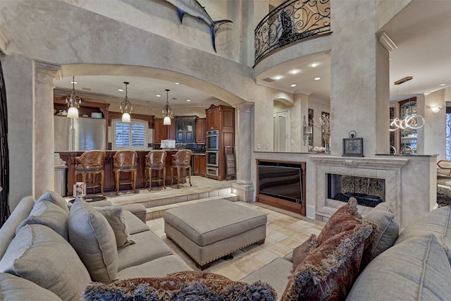 living room featuring recessed lighting, a premium fireplace, a high ceiling, and crown molding