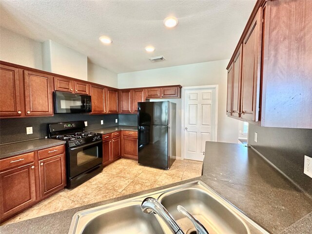 kitchen featuring a textured ceiling, black appliances, and light tile patterned flooring