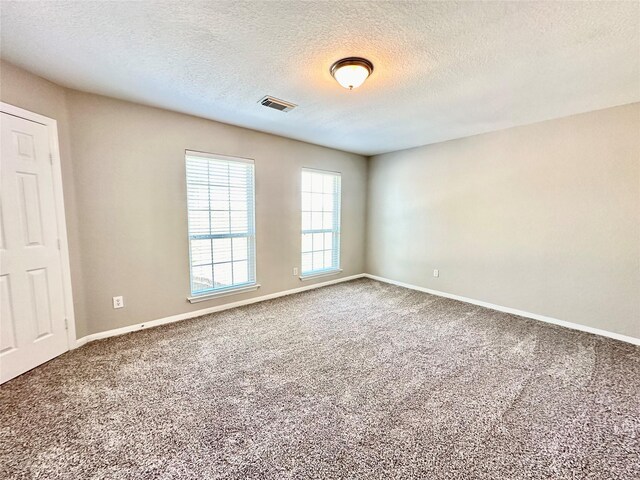 spare room featuring a textured ceiling and carpet